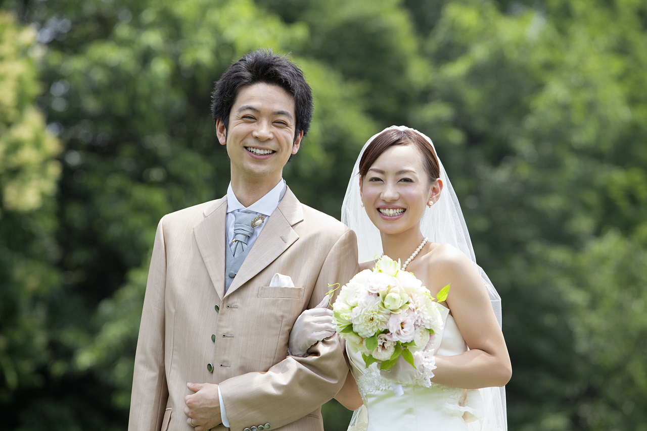 笑顔で腕を組む新郎新婦